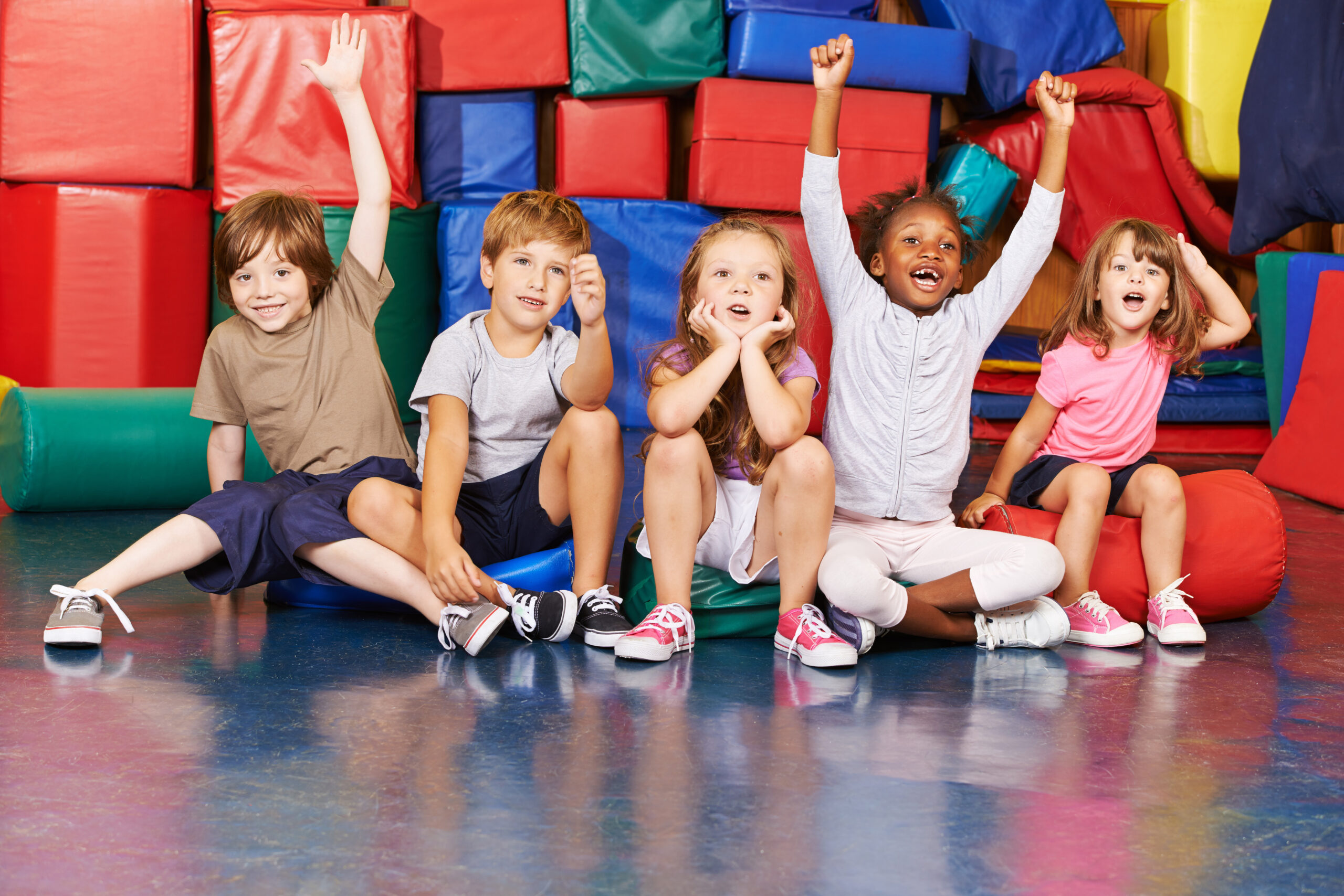 kids sitting and waving in gym